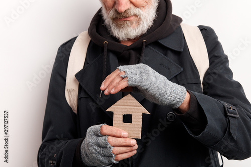 Fotomural unrecognizable old man wearing street clothes holding house made of cardboard, dream about shelter