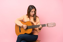 Young Brunette Girl With Guitar Over Isolated Pink Background