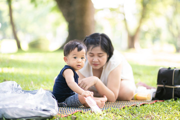 Mom playing with baby boy in city green park