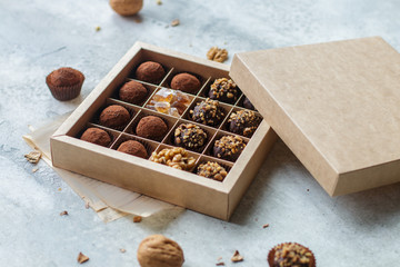 Set of chocolate truffles with nuts and cocoa. Tasty round candy. A delicious gift in a Kraft paper box. Holiday concept. Selective focus