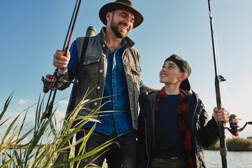 Wall Mural - Boy first time fishing with father. He curious and wants to learn how to fish and cook. He and father put on fishing clothes, took fishing rods.