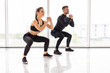 © F8  \ Suport Ukraine - Deep squat. Fitness couple in sportswear doing squat exercises at gym