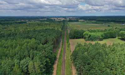 Wall Mural - Aerial drone perspective view on straight railroad in rural scenery with green forest during summer