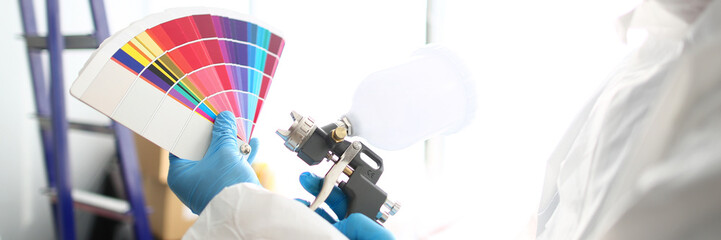 Hands of workman holding airbrush and colorful fantail picking wall