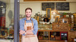 © marvent - Smiling young barista leaning against the entrance of a cafe