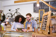 © marvent - Smiling baristas working on a tablet behind their cafe counter