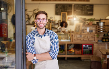 Friendly barista standing at the doorway of a trendy cafe