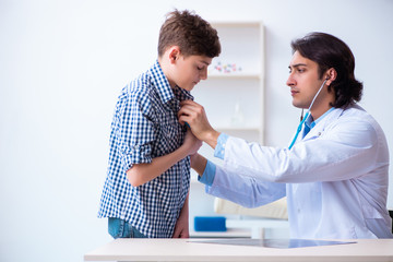 Male doctor examining boy by stethoscope