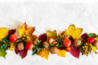 Dekoracja z jabłek, jarzębiny, liści i orzechów na jasnym tle z miejscem na napis