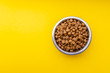 Dog food in a metal bowl. Yellow background