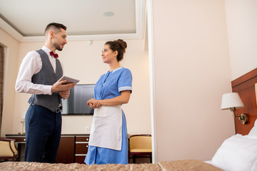 Aufkleber - Young elegant porter with touchpad looking at pretty chamber maid in uniform