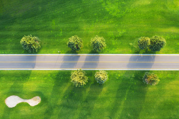 Wall Mural - aerial view of road through beautiful green field at sunset in autumn. beautiful landscape with empt