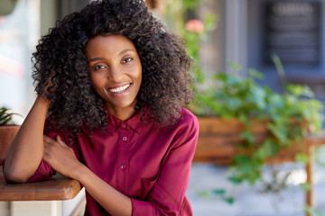 Wall Mural - Smiling African American woman sitting outside of her cafe