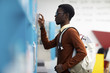 © Seventyfour - Side view portrait of African-American student choosing books standing by shelves in college library, copy space