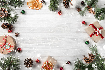 Wall Mural - creative frame made of christmas fir branches on white wooden background with red decoration, pine c