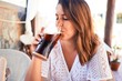 Young beautiful woman sitting at restaurant enjoying summer vacation drinking soda