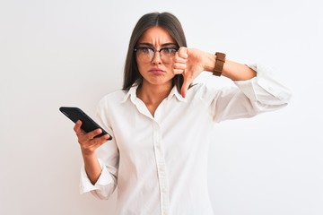 Wall Mural - Beautiful businesswoman wearing glasses using smartphone over isolated white background with angry face, negative sign showing dislike with thumbs down, rejection concept