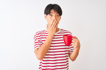 Wall Mural - Young chinese man drinking a cup of coffee standing over isolated white background cover mouth with hand shocked with shame for mistake, expression of fear, scared in silence, secret concept