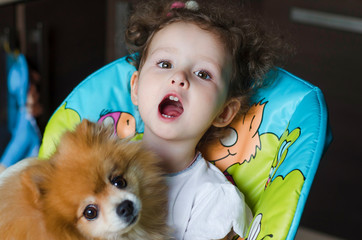 Portrait of little cute beautiful girl with fluffy Pomeranian dog. friends since childhood. joyful emotions. true friend. people and pet. soft focus. child and spitz