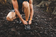 Man tying running shoes before trail running outdoors. Close-up