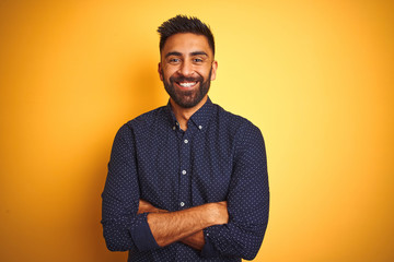 Wall Mural - Young handsome indian businessman wearing shirt over isolated yellow background happy face smiling with crossed arms looking at the camera. Positive person.