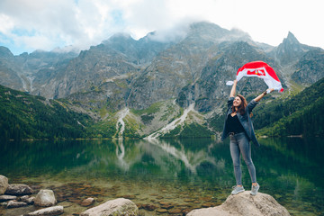 Wall Mural - young pretty woman with poland flag in mountains near lake