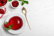 Delicious fresh red jelly with berries and mint on white wooden table, flat lay. Space for text