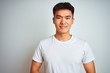 © Krakenimages.com - Young asian chinese man wearing t-shirt standing over isolated white background with hands together and crossed fingers smiling relaxed and cheerful. Success and optimistic