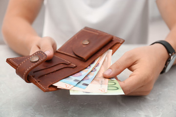 Man putting Euro banknotes in wallet, closeup