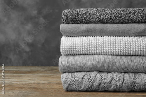 Fotografía Stack of warm clothes on wooden table against grey background