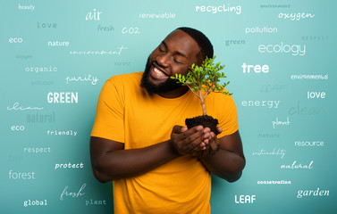 Wall Mural - Happy boy hugs a small tree ready to be planted over a light blue color. Concept of forestation, ecology and conservation with most important terms