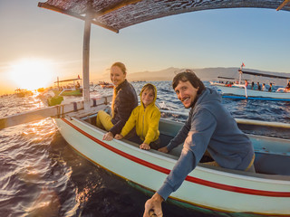 Happy family travelers meets dawn in the sea on a boat