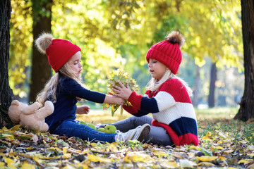 Two sweet little girl in the yellow leaves of autumn