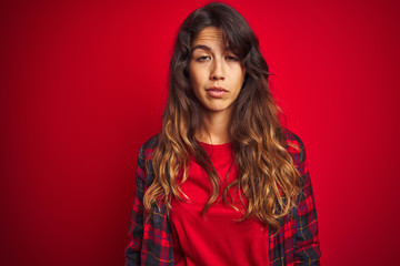 Wall Mural - Young beautiful woman wearing casual jacket standing over red isolated background looking surprised and shocked doing ok approval symbol with fingers. Crazy expression