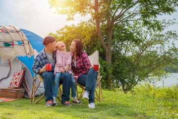 Wall Mural - Group of asian family travel and camping at lakeside in forest ,sitting all  together and smile. Family and outdoor activity concept.