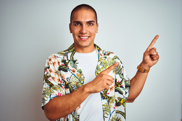 Poster - Young handsome man on holidays wearing Hawaiian shirt over white background smiling and looking at the camera pointing with two hands and fingers to the side.