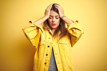 Poster - Young beautiful woman wearing denim jacket standing over yellow isolated background suffering from headache desperate and stressed because pain and migraine. Hands on head.