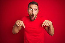 Young Handsome Man Wearing Casual T-shirt Over Red Isolated Background Pointing Down With Fingers Showing Advertisement, Surprised Face And Open Mouth