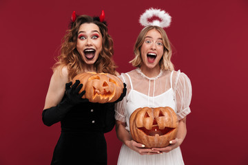 Poster - Positive women demon and angel in carnival costumes with pumpkin.