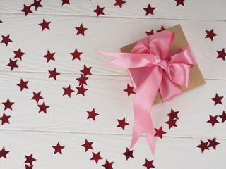 Wall Mural - gift box with bright red pink ribbon on white background with stars. space for text to postcard