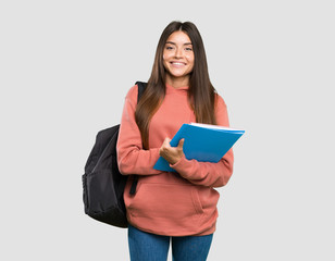 young student woman holding notebooks keeping the arms crossed in frontal position over isolated gre