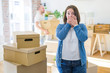 © Krakenimages.com - Young couple arround cardboard boxes moving to a new house, plus size woman standing at home shocked covering mouth with hands for mistake. Secret concept.