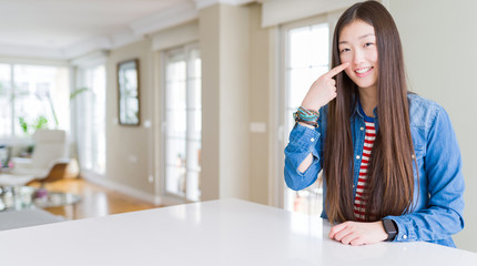 Sticker - Young beautiful asian woman with long hair wearing denim jacket Pointing with hand finger to face and nose, smiling cheerful. Beauty concept