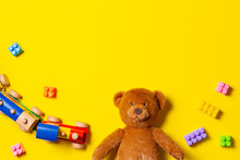 Baby Kids Toys Background. Teddy Bear, Wooden Train And Colorful Blocks On Yellow Background