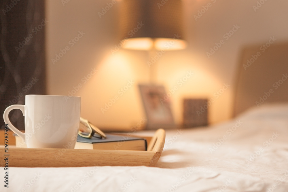 Cup of hot drink and book on bed - obrazy, fototapety, plakaty 