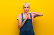 © luismolinero - Teenager girl with overalls on yellow background making time out gesture