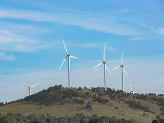 Wall Mural - an array of large wind turbines moving to create kinetic energy for renewable energy supply on a sun