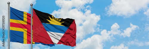 Fotomural Aland Islands and Antigua and Barbuda flag waving in the wind against white cloudy blue sky together