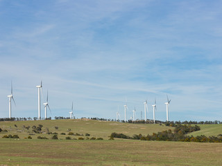Wall Mural - an array of large wind turbines moving to create kinetic energy for renewable energy supply on a sun