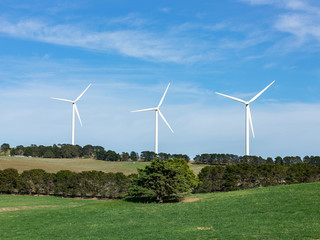 Wall Mural - three large wind turbines moving to create kinetic energy for renewable energy supply on a sunny day